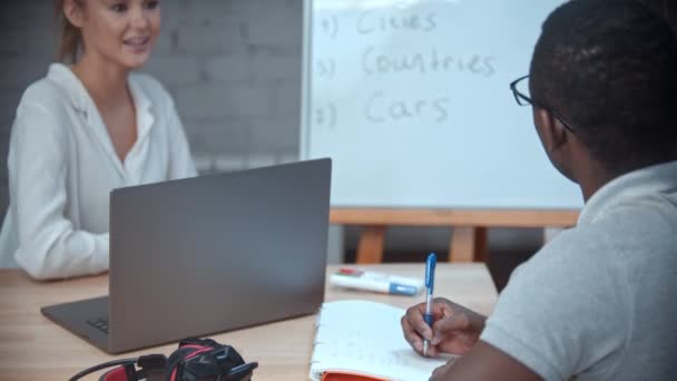 Lehrerin erteilt einem Mann Englischunterricht - ein Mann macht sich Notizen — Stockvideo