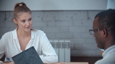 Beyaz bir kadın ve siyah bir adam İngilizce dersi alıyor. Laptopun başında oturan bir adam.