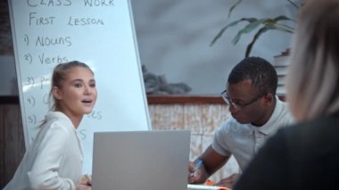 Beyaz bir kadın ve siyah bir adam İngilizce dersi alıyor. Öğretmen onları izliyor.
