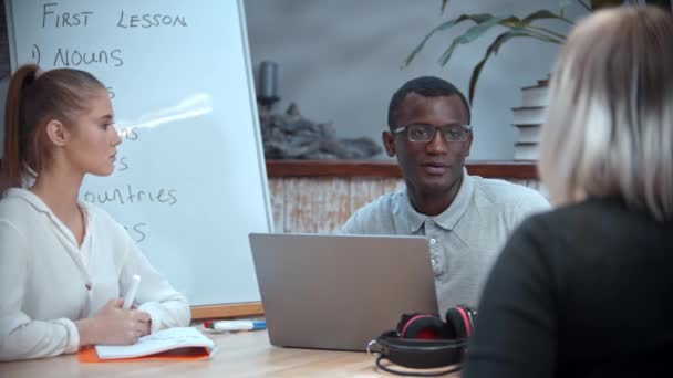 Femme blanche et homme noir ayant une leçon d'anglais au bureau moderne et parlant avec leur enseignante — Video