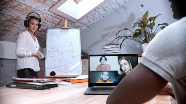 An online maths lesson - woman standing by the board and her students on the screen of the laptop listening to her — Stock Video