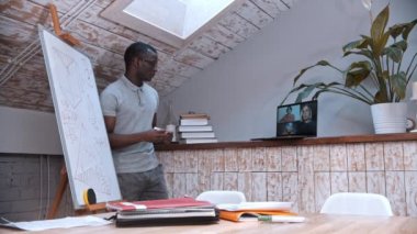 Çevrimiçi matematik dersi. Gözlüklü Afro-Amerikan bir öğretmen tahtada duruyor ve öğrencilerine ekrandaki materyalleri anlatıyor.