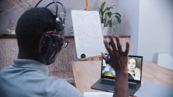 Een online wiskundeles - een zwarte leraar groet zijn leerlingen op het scherm van de laptop — Stockvideo