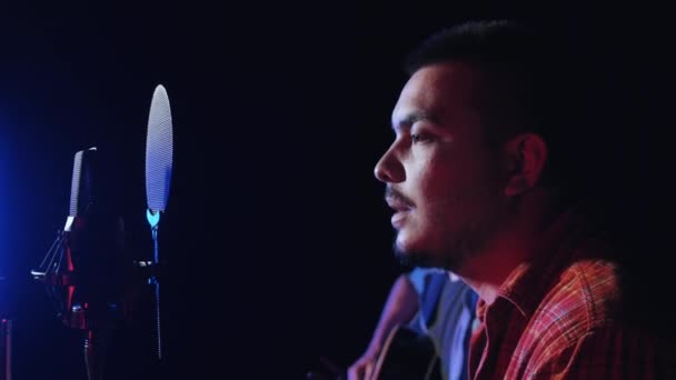 Dois homens gravando uma música indie no estúdio tocando guitarra e cantando em microfone — Vídeo de Stock