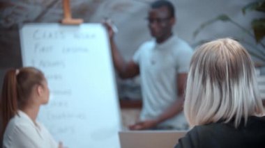 Afrika kökenli bir Amerikan öğretmeniyle İngilizce dersi. Masada oturan ve dinleyen iki kadın.