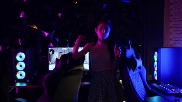 Genç seksi kadın neon oyun kulübünde joystick tutuyor ve sakız üflüyor. — Stok video