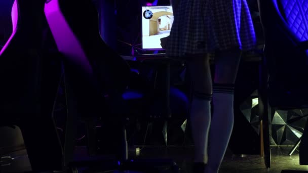 Genç seksi kadın bilgisayar kulübünde bilgisayara gelir, golf çoraplarını yukarı çeker ve sandalyeye oturur. — Stok video