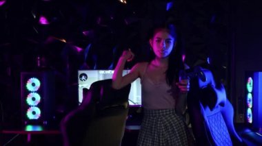 Neon oyun kulübünde elinde joystickle sakız tutan çekici genç bir kadın.