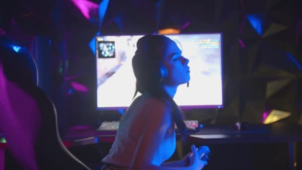 Mujer joven jugando un juego en el club de juego - se da la vuelta y saludando con un joystick — Vídeo de stock