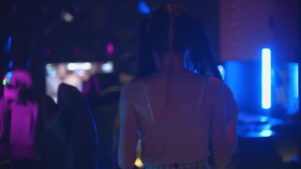 Молодая привлекательная женщина с хвостиком гуляет в игорном клубе - стоя у стула и держа в руках джойстик — стоковое видео