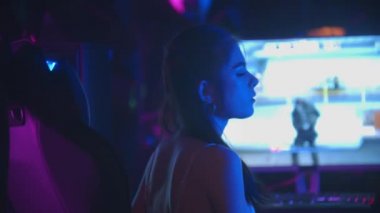 Oyun kulübündeki genç seksi kadın ağzından sakız çıkarıyor ve kameraya bakıyor.