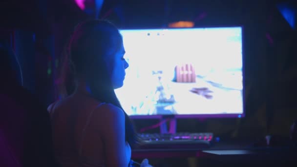 Young sexy woman playing a game in gaming club - turns around and pulling a bubble gum out of her mouth — Stock Video