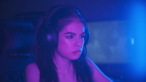 Ung attraktiv kvinna sitter i neon gaming klubb och spela spel - bita hennes läpp - vinna spelet och blir glad — Stockvideo