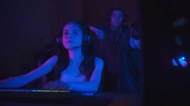 Neon oyun kulübünde online oyun oynayan iki güzel oyuncu kız arkadaşları onlara gelir ve konuşmaya başlar.