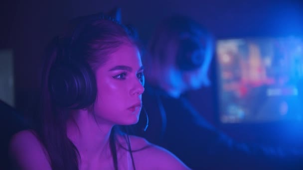Две девушки играют в онлайн-игру в неоновом игровом клубе — стоковое видео