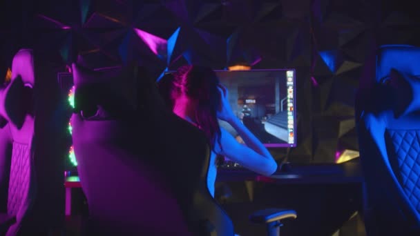 Fiatal csinos nő ül a neon játék klub és a játék - feláll a székből, és elsétál — Stock videók