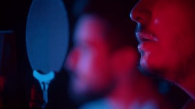 Gitar çalan bir adam ve neon ışıkta şarkı söyleyen başka bir sakallı adam.