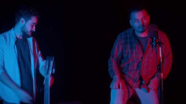 Deux hommes s'assoient dans le studio d'enregistrement sombre et commencent à enregistrer une chanson — Video