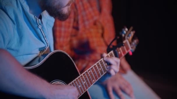 Dos hombres se sientan en el escenario e interpretan una canción de guitarra indie — Vídeos de Stock