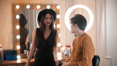 Çekici bir erkek model sandalyede oturuyor ve makyaj yapmadan önce yüzünü temizliyor.