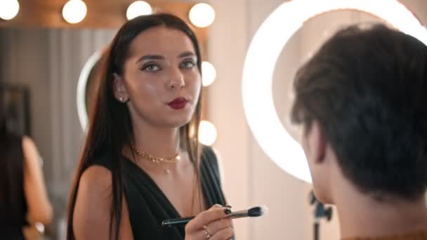 Make up artist applicera bas på ansiktet av manliga modellen med en borste — Stockvideo