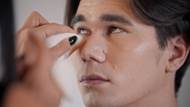 Woman make up artist applying concealer on the face of male model with a pad — Stock Video