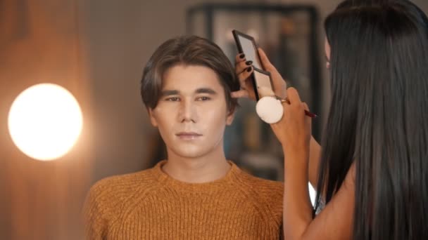 Kobieta makijaż artysta stosowanie kontur odcienie na twarzy Azji mężczyzna model za pomocą pędzel — Wideo stockowe