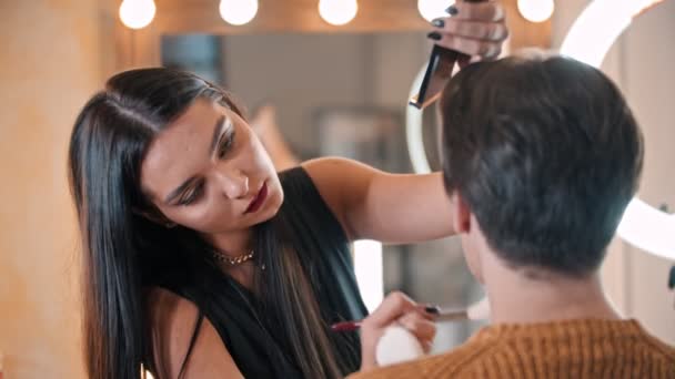 Make-up-Künstlerin trägt Konturschattierungen auf einem Kiefer des männlichen Modells mit einem Pinsel auf — Stockvideo