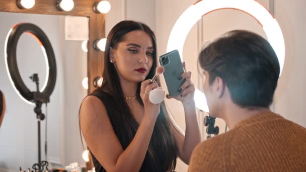 Maquilleuse prenant des photos de mannequin masculin avec maquillage - ajoutant une touche finale — Video