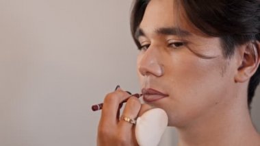 Makyaj stüdyosu - Makyöz erkek modelin dudak kenarına kırmızı dudak kalemi sürüyor