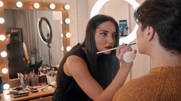 Makeup studio - makeup artist applying lipstick on the lips of male model using a brush — Stock Video