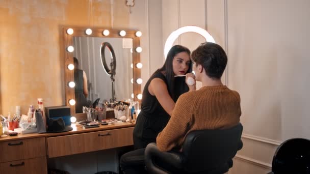 Estúdio de maquiagem - artista de maquiagem aplicando batom nos lábios de seu modelo masculino usando um pincel — Vídeo de Stock