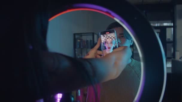 Makeup studio - γυναίκα καλλιτέχνης κινηματογραφεί ένα βίντεο του ανδρικού μοντέλου της με μακιγιάζ - τολμηρή εμφάνιση με κόκκινα χείλη — Αρχείο Βίντεο