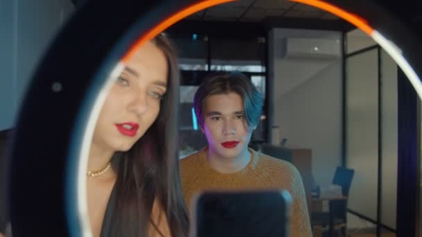 Make-up-Studio - junger gutaussehender Mann mit fettem roten Lippenstift und seinem Maskenbildner, der gerade dabei ist, ein Video zu drehen — Stockvideo