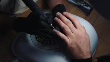 Hırdavatçı manikürü. Manikür ustası, erkek eli üzerinde küçük bir matkapla manikür yapıyor.