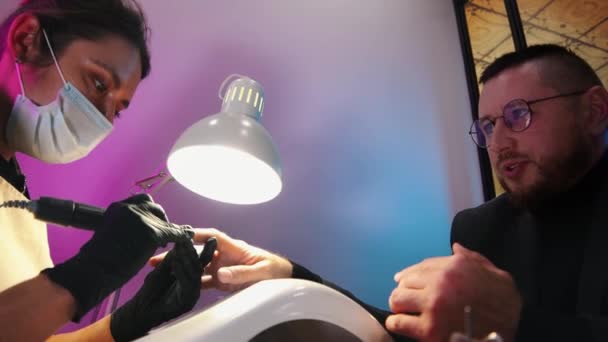 A business man having his nails done in salon and talking with his master — Stock Video