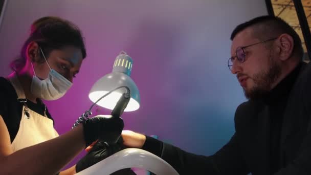 A business man in grey costume having his nails done in salon and talking with his master — Stock Video