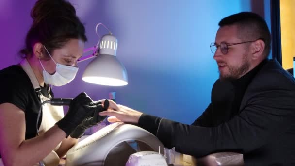 Un homme d'affaires en lunettes rondes se fait faire les ongles dans le salon de beauté — Video