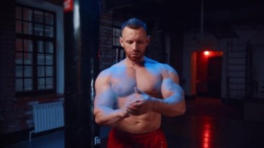 Spor salonunda ellerini tebeşirle kaplayan güçlü bir adam.