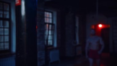 Güçlü adam spor salonuna girer ve kameraya bakar.