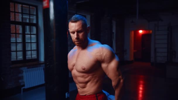 Homem forte de pé no ginásio e mostrando seus músculos — Vídeo de Stock