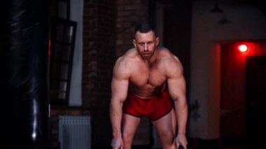 Spor salonunda duran ve halat egzersizleri yapan sert adam.