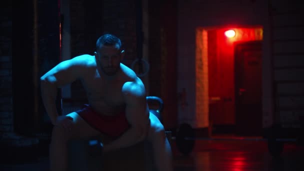 Tvrdý muž čerpá své biceps v kontrastním osvětlení a dívá se do kamery — Stock video