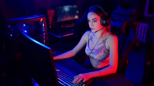 Concepto de juego - mujer atractiva joven se sienta en la silla en el club de juegos de neón y jugar juegos — Vídeos de Stock