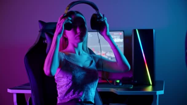 Uma garota gamer sentado ao lado do PC - colocando em seus fones de ouvido e começa a jogar — Vídeo de Stock