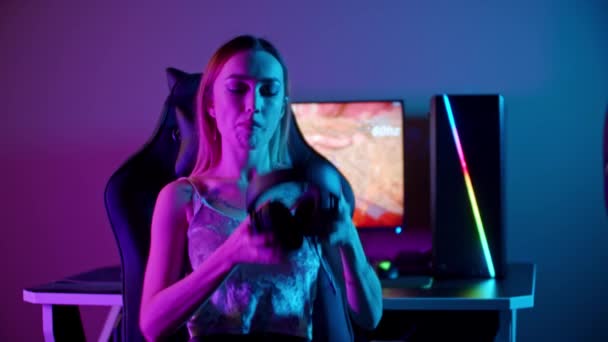 Tätowiertes Spielermädchen sitzt am PC - setzt sich die Kopfhörer auf und spielt los — Stockvideo