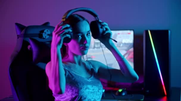 Tatuado gamer mulher sentado ao lado do PC - colocando em seus fones de ouvido e começa a jogar — Vídeo de Stock