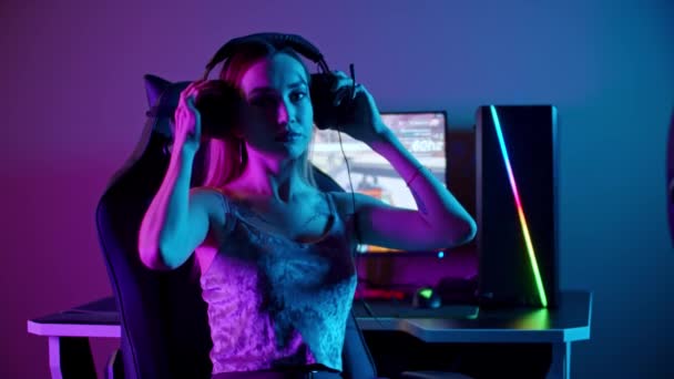 Menina gamer tatuado sentado ao lado do PC - colocando em seus fones de ouvido e vira-se para o monitor — Vídeo de Stock