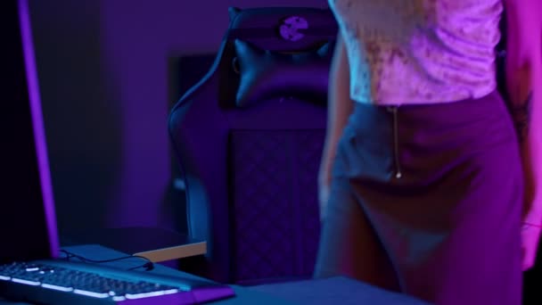 Tätowiertes Spielermädchen im sexy Tank-Top sitzt am PC - setzt sich die Kopfhörer auf und spielt los — Stockvideo