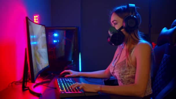 Jovem gamer mulher no respirador sentado ao lado do PC e jogando um jogo — Vídeo de Stock